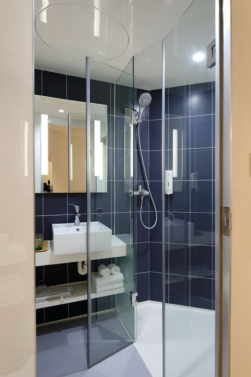 Glass shower enclosure with dark blue wall tile
