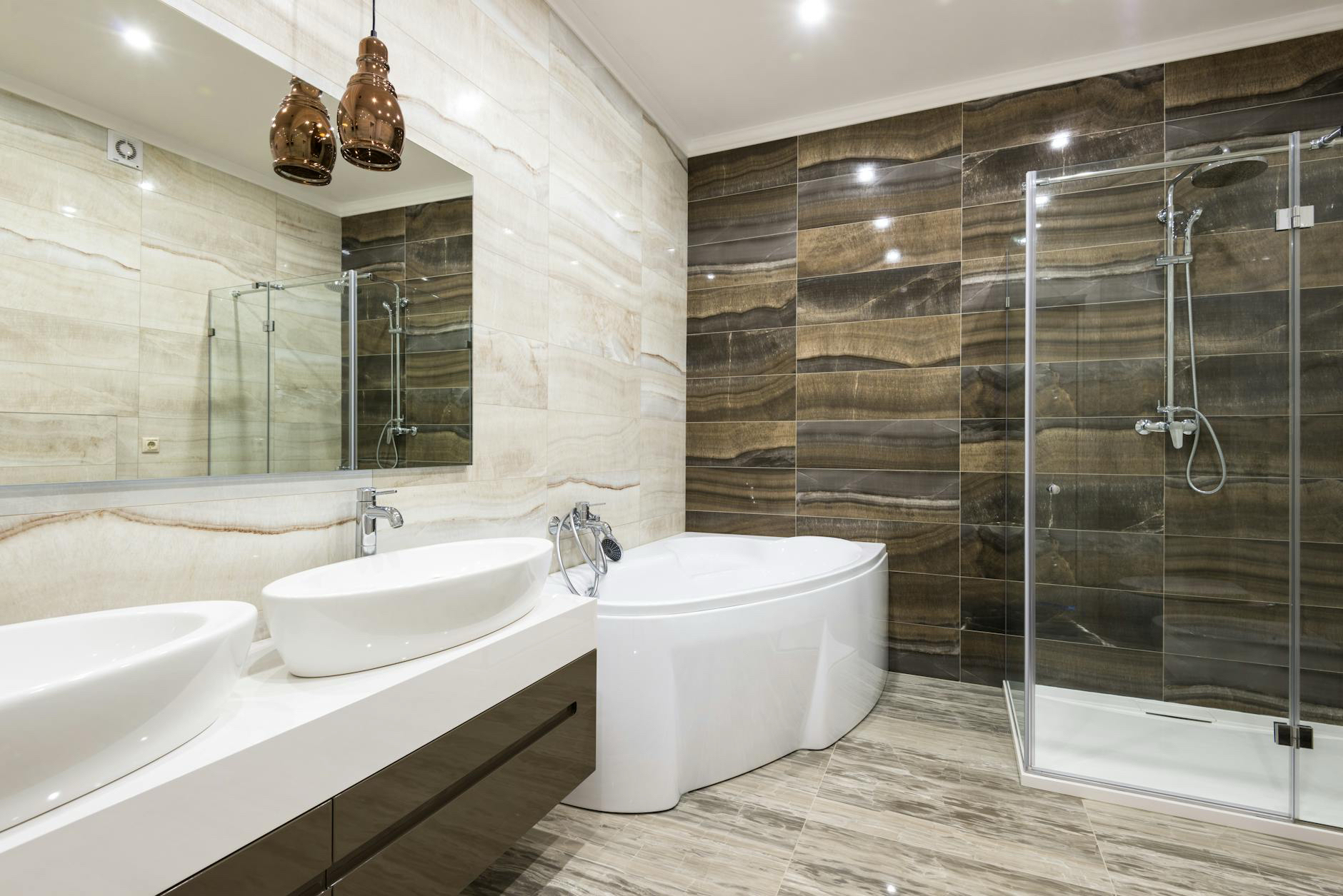 Bathroom inspiration with stone-look walls, twin basins, a bathtub and glass shower